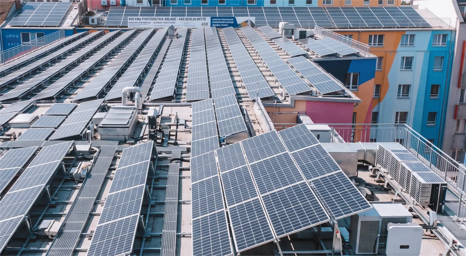 Dach-Photovoltaik auf dem A&O Hostel Berlin Mitte — PV-Reihen über dem Innenhof mit bunten Fassaden