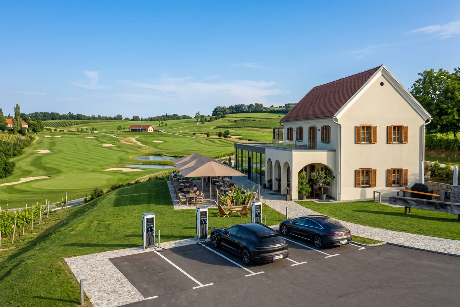 Golf-Clubhaus der Murhof Gruppe mit Ladesäulen — zwei E-Autos laden vor der Terrasse, dahinter der Golfplatz